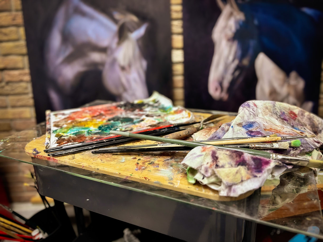 Palet met verf en paardenschilderijen in het atelier Palet met verf en paardenschilderijen in het atelier